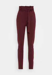 Burgundy trousers with a high waistband and fabric tie. Slim fit, two side pockets, smooth texture, and tapered legs.
