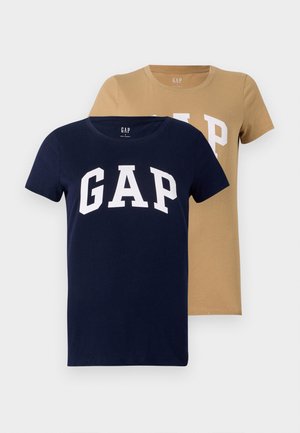Two short-sleeve T-shirts in navy and tan colors, made of cotton. Both feature a large white "GAP" logo on the front.