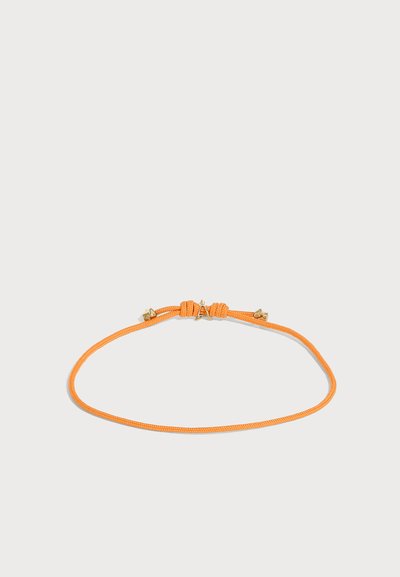 Bracelet fin en cordon tressé orange avec des nœuds ajustables et de petits accents métalliques dorés sur un fond clair uni.