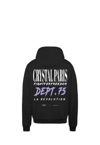 Mustat hupparit, joissa on suuri valkoinen ja violetti graafinen kuvio selässä. Tekstit sisältävät "CRYSTAL PARIS", "DEPT. 75" ja "LA RÉVOLUTION."