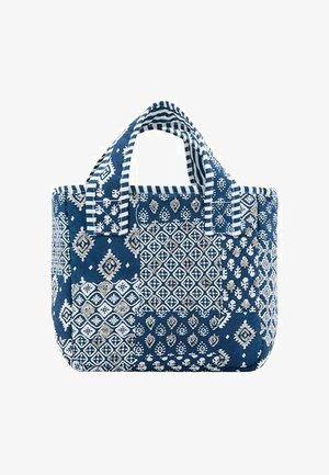 Sac fourre-tout patchwork bleu et blanc avec des motifs floraux et géométriques et des poignées courtes rayées.