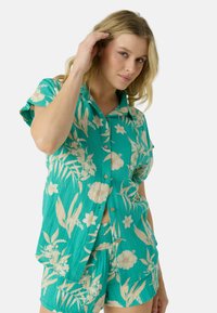 Turquoise overhemden met knopen en bijpassende shorts, voorzien van een bloemmotief in roomwit en zachtgeel, gemaakt van lichtgewicht stof met een textuurlijk oppervlak.