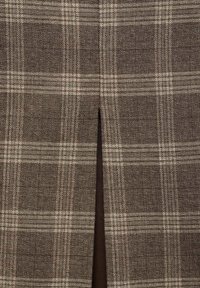 Tissu en tartan marron avec une texture fine, présentant un motif tissé subtil et une fente avant pour un intérêt design supplémentaire.