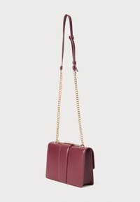 Sac à main en cuir bordeaux avec un design structuré, doté d'une chaîne en or comme bandoulière et de deux accents verticaux à l'avant.