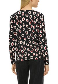 Langärmliges schwarzes Oberteil mit einem mehrfarbigen Leopardenmuster in Weiß und Rot. Weicher Stoff mit einem rundem Ausschnitt und normaler Passform.