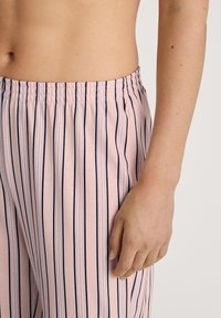 Ljusrosa pyjamasbyxor med vertikala marinblå och persikofärgade ränder, elastisk midja och mjukt bomullsmaterial, med en avslappnad passform.