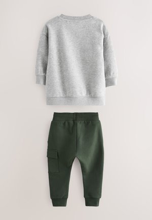 Hall halli dressipluus soonikkoelise kaeluse ja varrukaservadega, kombineeritud tumeroheliste pükstega, millel on elastne vöökoht ja külgmine laokott.