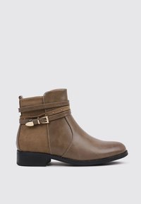Bota de tobillo marrón de cuero sintético con textura suave, que presenta correas decorativas y una hebilla en tono dorado, con tacón bajo negro.