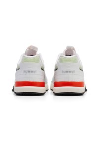 Baskets de sport blanches avec un dos texturé, présentant un accent rouge au talon, une semelle noire et des détails en mesh vert sur le dessus. Logo de la marque affiché.