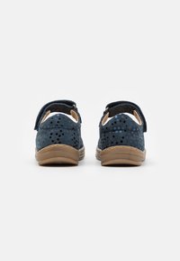 Granatowe buty z perforowanej zamszowej cholewki, regulowanym zapięciem na rzep oraz teksturowaną gumową podeszwą. Płaska konstrukcja z zaokrąglonym tyłem.