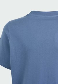 Camiseta de algodón azul que muestra el cuello de la parte posterior y el área de los hombros; textura suave con un diseño de cuello redondo, mangas cortas y corte regular.