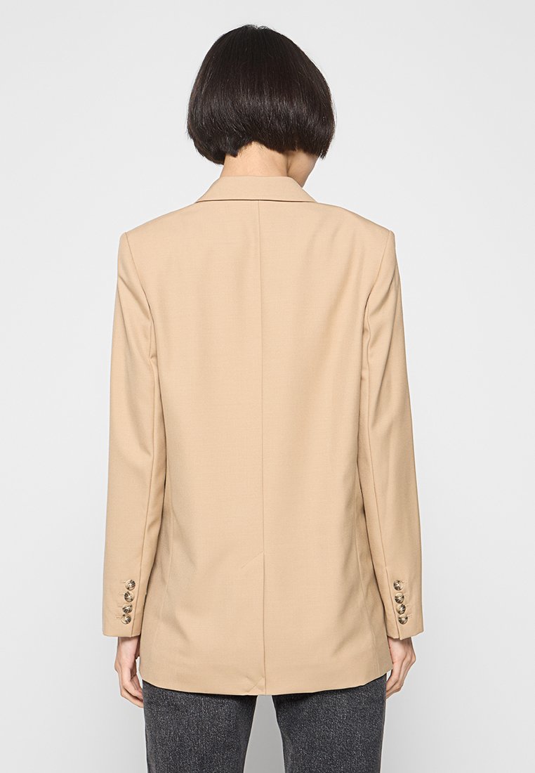 Beiger taillierter Blazer mit glatter Textur, der einen einzelnen Schlitz auf der Rückseite und fünf knopfartige Akzente an jedem Ärmel aufweist.