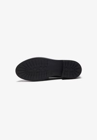 Zwarte rubberen schoenen zool met gemetste loopvlakken voor grip. Rechthoekige en ovale patroon details, die duurzaamheid en ontwerp voor tractie tonen.