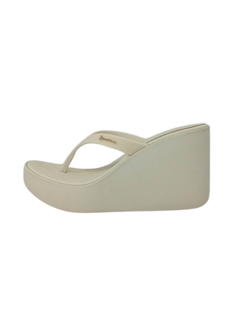Sandali con zeppa beige dal finish liscio, con design a fascia per le dita e tacco largo. La suola è leggermente arrotondata per garantire comfort.
