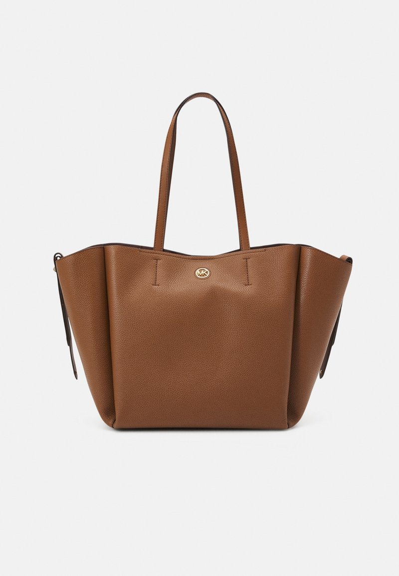 Sac cabas en cuir marron avec deux longues anses et un petit logo rond doré au centre avant sur fond blanc uni.