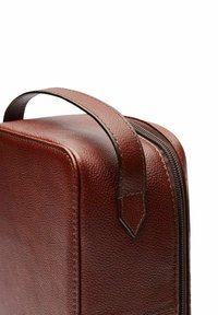 Bruine leren tas met een gestructureerd oppervlak, voorzien van een stevige handgreep aan de bovenkant en een rits aan de zijkant voor sluiting.