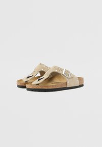 Beige suède sandalen met studs, kurken tussenzool en een zwarte rubberen loopzool. Open teen ontwerp met een band en een gesp detail.