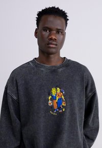 Donkergrijze oversized sweatshirt met een ronde hals en verlaagde schouders, met een kleurrijk borduurontwerp van twee figuren op de voorkant.
