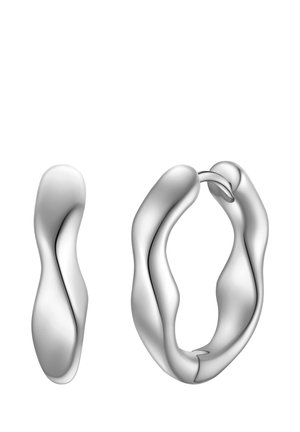 Boucles d'oreilles en argent en forme organique fluide, avec une surface lisse et des courbes continues. Une boucle est ouverte, l'autre est légèrement tordue.