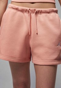 Rosa bomullsshorts med snörning i midjan, med en mjuk textur, sydda fållar och en liten logotyp på benet.