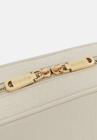 Kremfärgad läderkuvert med präglad logotyp, guldhardware och ett centralt blixtlås med ett distinkt tag som är ingraverat med "Valentino."