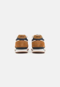 Brown suede and white mesh sneakers with navy accents. Features a padded collar and heel tab with "1973" imprint. Rubber outsole for grip.