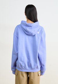 Confezionato in morbido tessuto, questo hoodie viola chiaro presenta un ampio cappuccio e un piccolo logo sulla parte superiore della schiena. Vestibilità ampia con spalle scese.