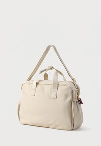Beżowa torba wykonana z gładkiego materiału z podwójnymi uchwytami u góry. Posiada zamek błyskawiczny oraz kolorowy chwost z boku.
