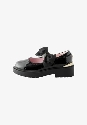 Chaussure Mary Jane en cuir verni noir avec semelle épaisse, intérieur rose, grand nœud en tissu et accent doré au talon.