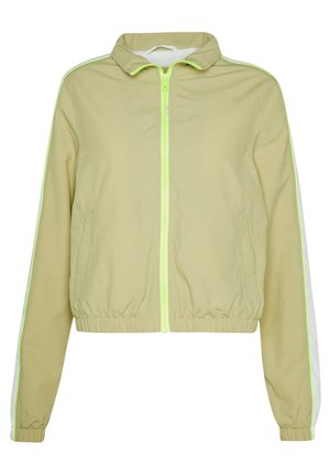 Giacca a vento verde chiaro con zip frontale, vita elastica e strisce bianche ai lati. Realizzata in un materiale liscio e leggero.