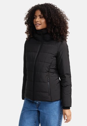 Black padded jacket with a high collar, zip closure, and side pockets. Features quilted texture and ribbed cuffs. Paired with blue jeans.