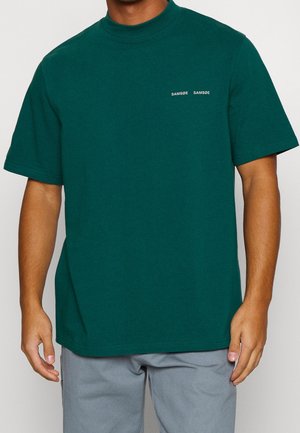 Teal cotton t-shirt with a high neckline, short sleeves, and standard fit. Features small white text logo on the left chest.