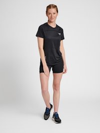 Svart atletisk t-shirt med korta ärmar, med texturerad tyg och en åtsittande design. Bärs med svarta shorts och svarta sneakers med blå accenter.
