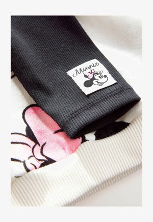 Manga negra acanalada con parche de Minnie Mouse, con acentos en rosa. La parte inferior tiene una tela blanca con un diseño de Minnie Mouse en rosa y negro.