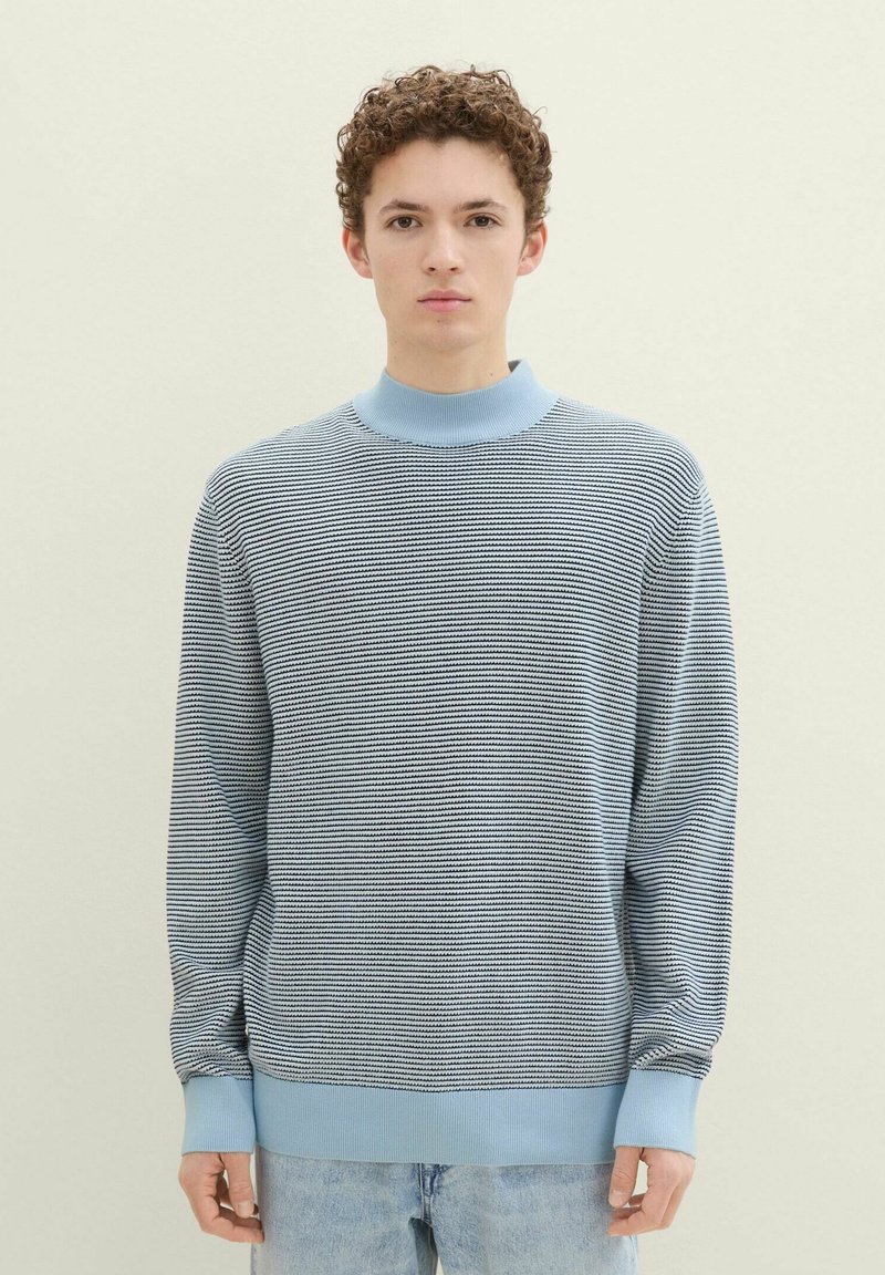 Niebieski sweter w paski, wykonany na drutach, z wysokim ściągaczem i długimi rękawami, charakteryzujący się miękką teksturą i luźnym krojem.