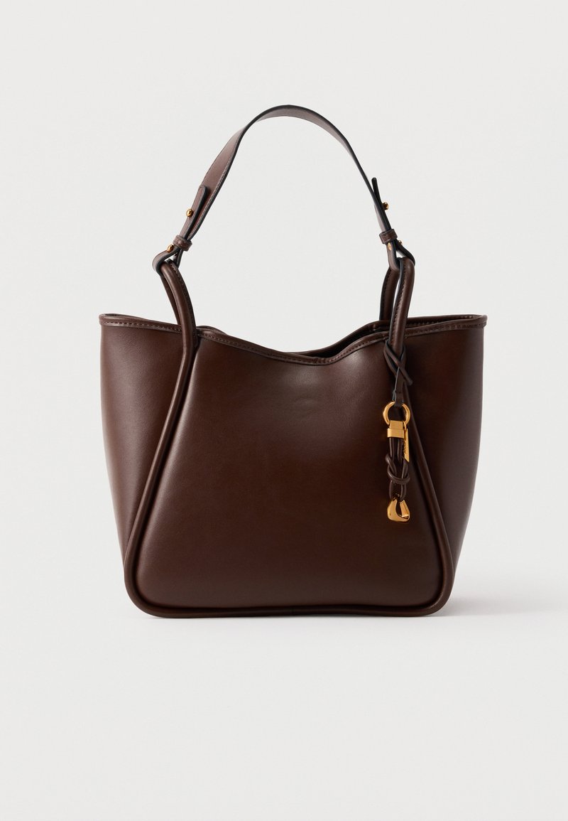 Mørkebrun lærhåndveske med en enkelt skulderstropp og en dekorativ spenne i gulltone som henger på høyre fremre side.