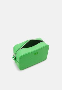 Gr�üne texturierte Toilettentasche mit einem Reißverschluss, rechteckiger Form und einem kleinen Logo auf der Vorderseite. Das Innere ist gefüttert und geräumig.