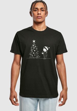 Sort bomulds t-shirt med et hvidt grafisk motiv af et barn med et juletræ, pyntet med julekugler og en stjerne på toppen.