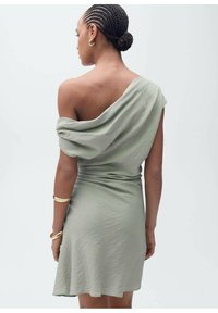 Green, off-the-shoulder dress made of soft fabric. Features a fitted waist and flows gently, showcasing a relaxed, draped design.