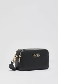 Μαύρη τσάντα crossbody από δέρμα με υφή, με χρυσά φερμουάρ, χρυσό λογότυπο "LIU JO MILANO" και αποσπώμενο λουράκι καρπού σε λευκό φόντο.