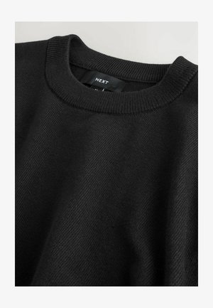Pull noir avec un col rond, des poignets côtelés et une texture lisse avec un motif diagonal subtil. Étiquette de la marque affichée en évidence.