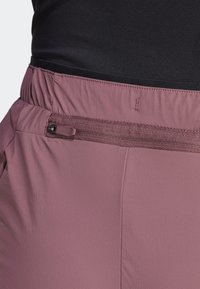 Rosa utomhusshorts med en texturerad finish, som har ett elastiskt midjeband och en dragkedjeficka på vänster sida för förvaring.