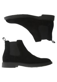 Bottes chelsea en suède noir avec des panneaux élastiques sur les côtés et une languette, présentant une semelle en caoutchouc et un design minimaliste.