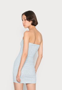 Vestido mini justo sem alças em azul claro com padrão floral branco, tecido suave, design justo ao corpo e comprimento até meio da coxa.