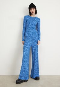 Blue long-sleeve top and flared pants set in a textured pattern. The fabric is stretchy. Paired with black clogs and a knit beanie.