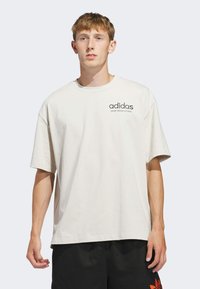 Light beige oversized t-shirt made of cotton, featuring a round neckline and short sleeves, with the Adidas logo printed on the chest.