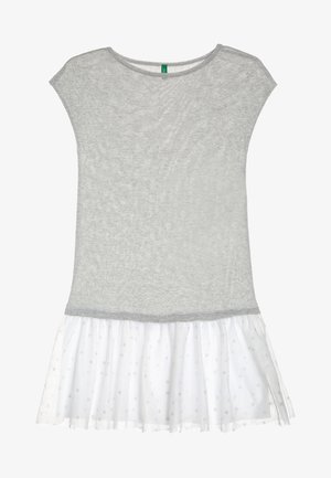 Jasnoszary top z krótkim rękawem i okrągłym dekoltem, zestawiony z białą, przezroczystą spódnicą z delikatnym wzorem w groszki i falbaną na dole.