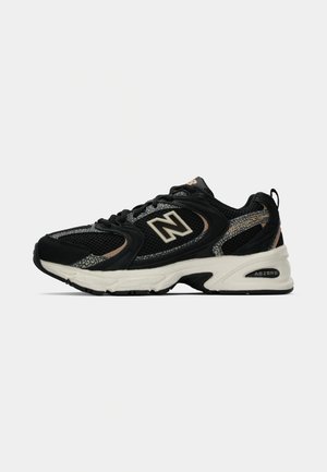 Zwarte en beige New Balance 530 sneaker met een bovenwerk van mesh en suede, witte gevoerde zool en ABZORB dempingstechnologie.