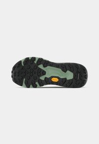 Black rubber outsole with green accents, featuring a textured grip pattern and Vibram logo. Designed for traction and stability.