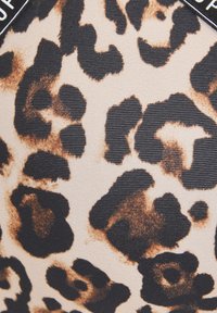 Tkanina s leopardím vzorom s hladkou textúrou, obsahujúca veľké čierne škvrny na béžovom pozadí, zvýraznené jemným žíhaním.